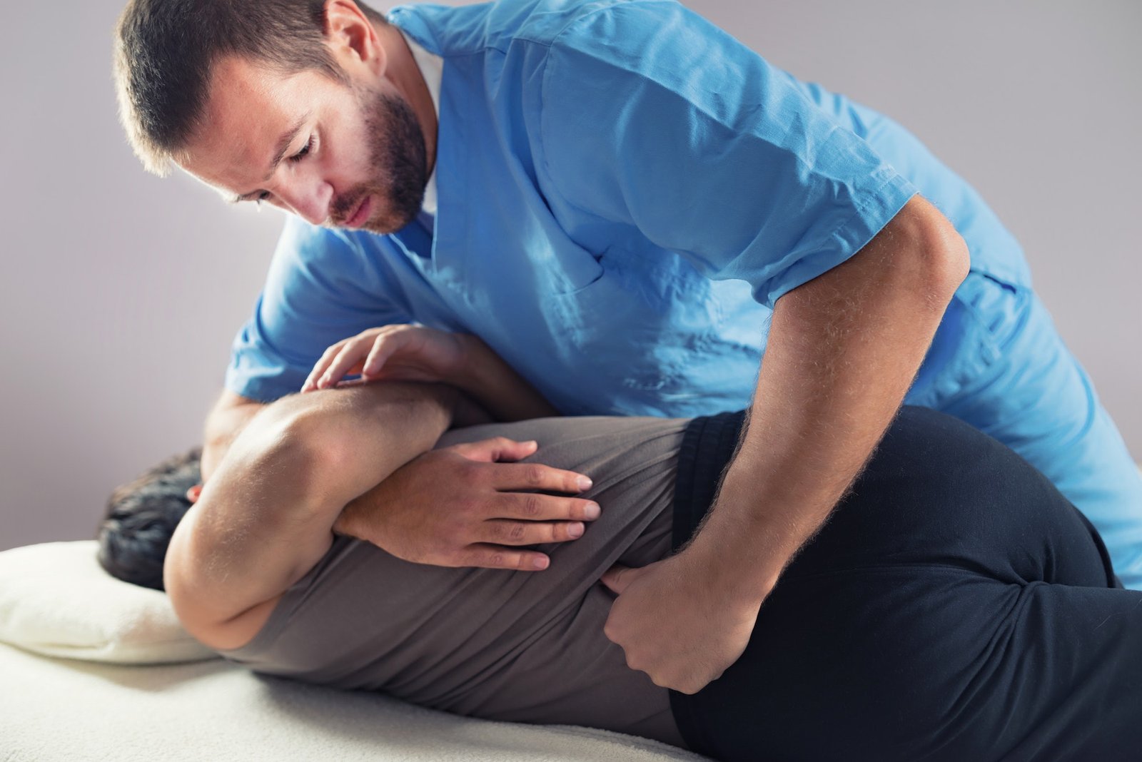 Osteópata realizando tratamiento manual en la espalda de un paciente adulto
